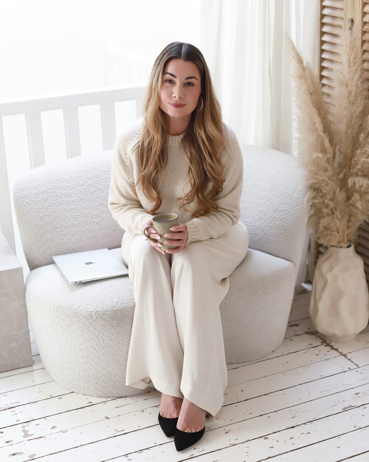 Sabine Saindrenan in een lichte stoel met een kop koffie